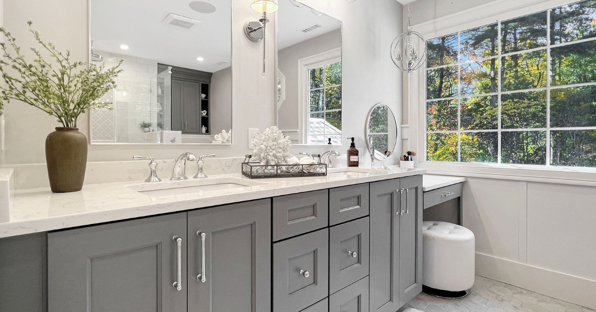 Light and airy primary bathroom renovationwith a double vanity in a blue/gray paint color with white stone countertops, a makeup vanity, and a walk-in shower with three showerhead options.