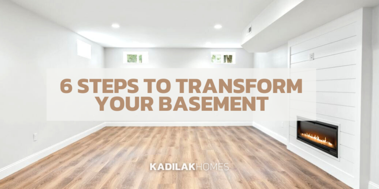 A bright and modern basement interior with white walls and a faux fireplace embedded in a textured white wall. The room features hardwood flooring and recessed lighting. A small window allows natural light in. Text overlay reads '6 STEPS TO TRANSFORM YOUR BASEMENT' in bold letters, with the logo of 'KADILAK HOMES' in the bottom right corner.