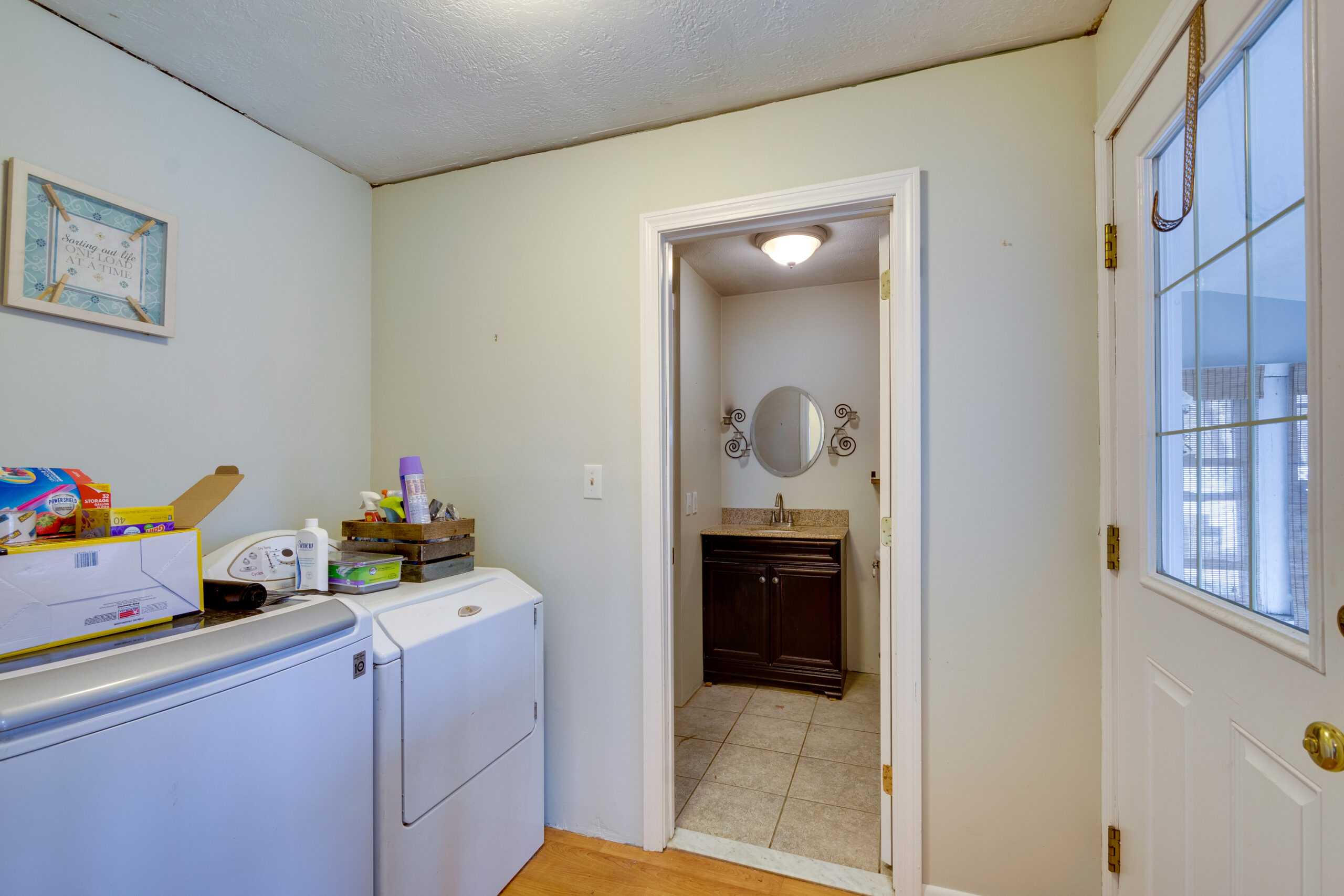 Before image of a laundry room in a vintage New England home showing outdated appliances and cluttered space prior to renovation