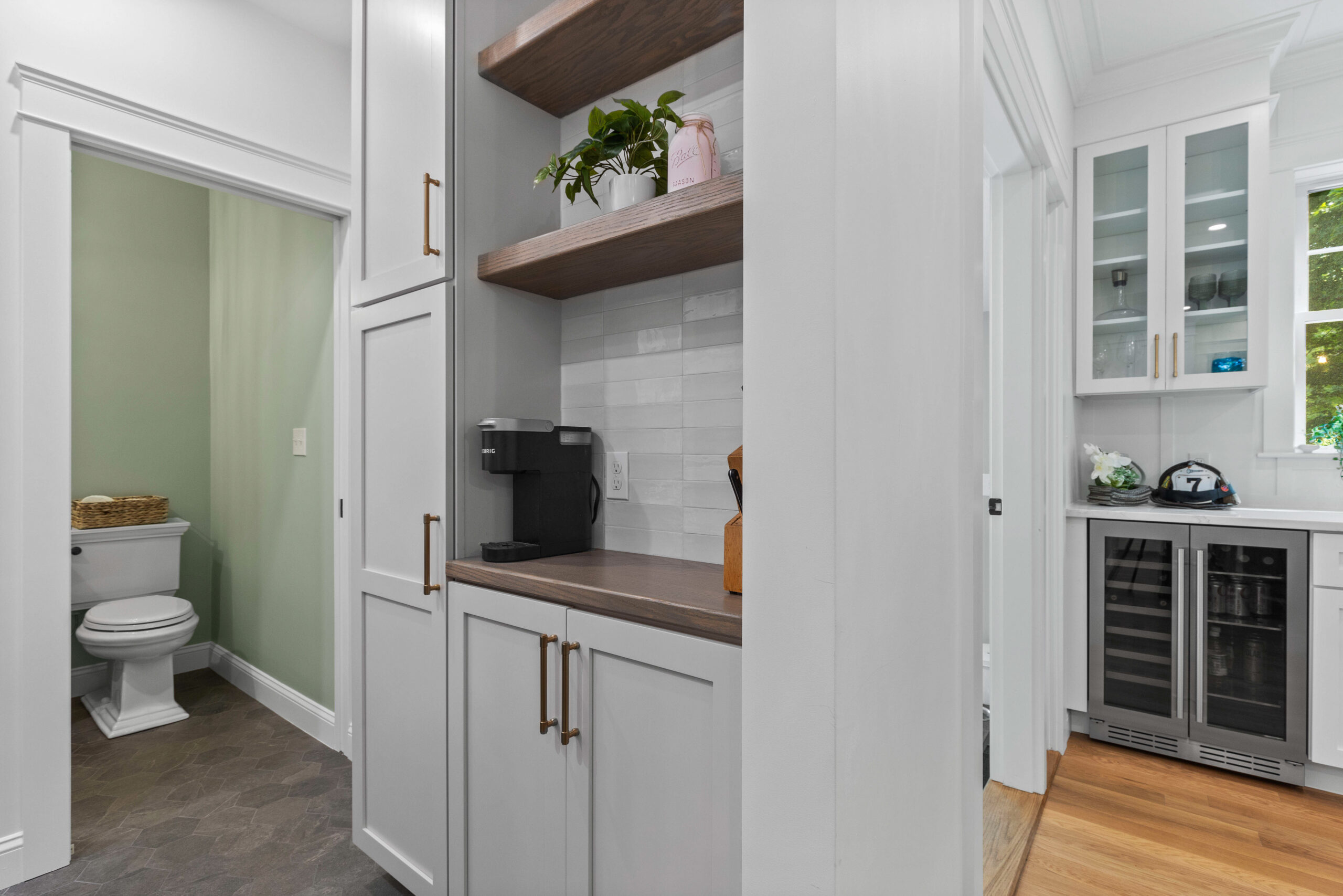 After image of a renovated coffee nook and adjacent bathroom in a vintage New England home, showcasing modern cabinetry, stylish open shelving, and a refreshed bathroom with elegant fixtures