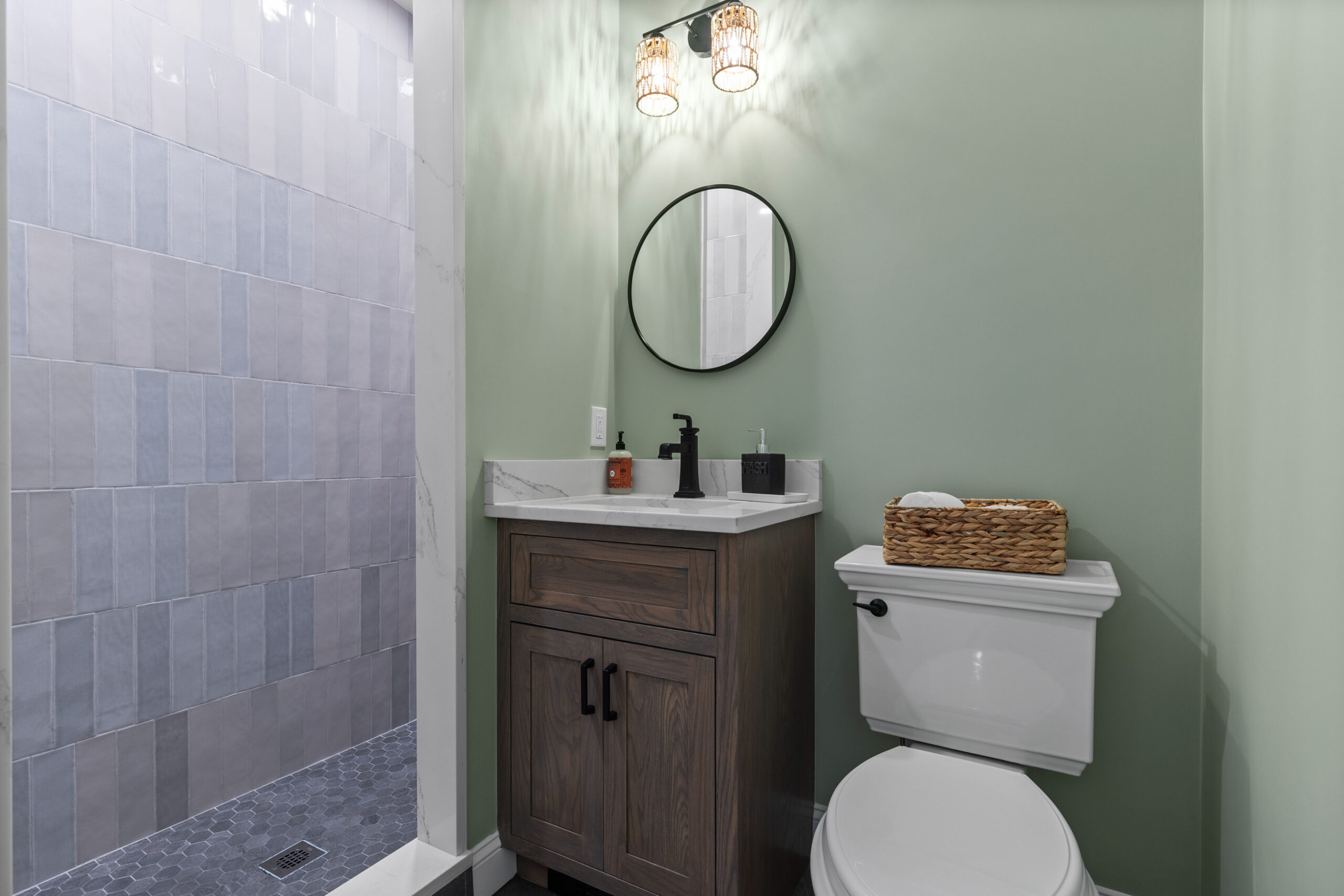Beautifully renovated bathroom in a vintage New England home, featuring a modern vanity, chic mirror, and a stylish walk-in shower with elegant varied crackled subway tilework."