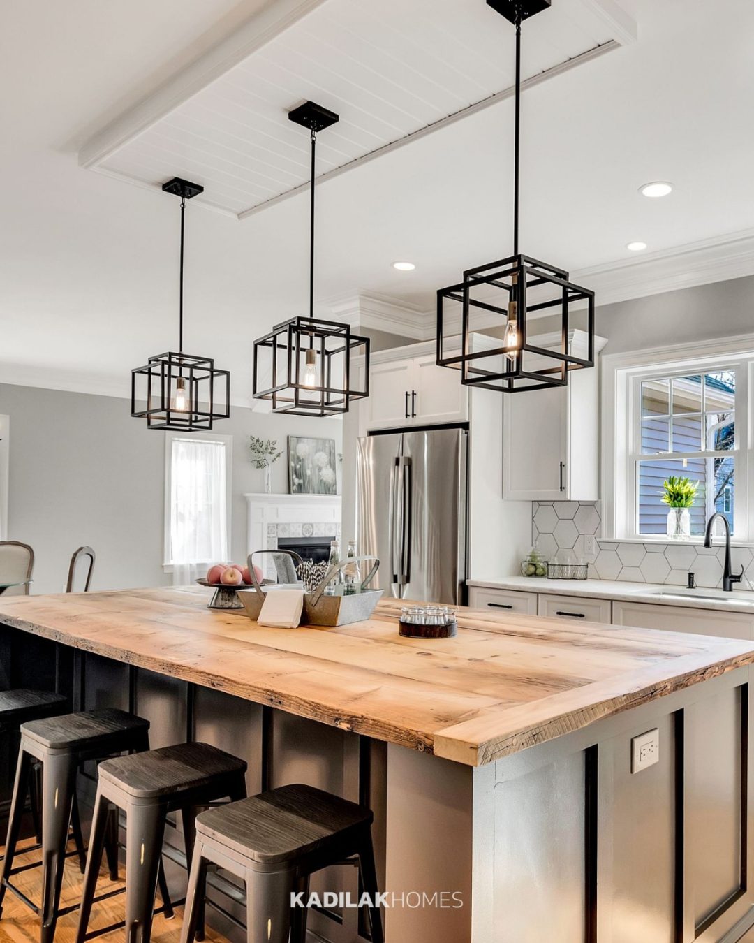 Taubert Pendant by Kichler Lighting with an open black geometric frame hanging above a rustic wood kitchen island in a modern farmhouse kitchen.