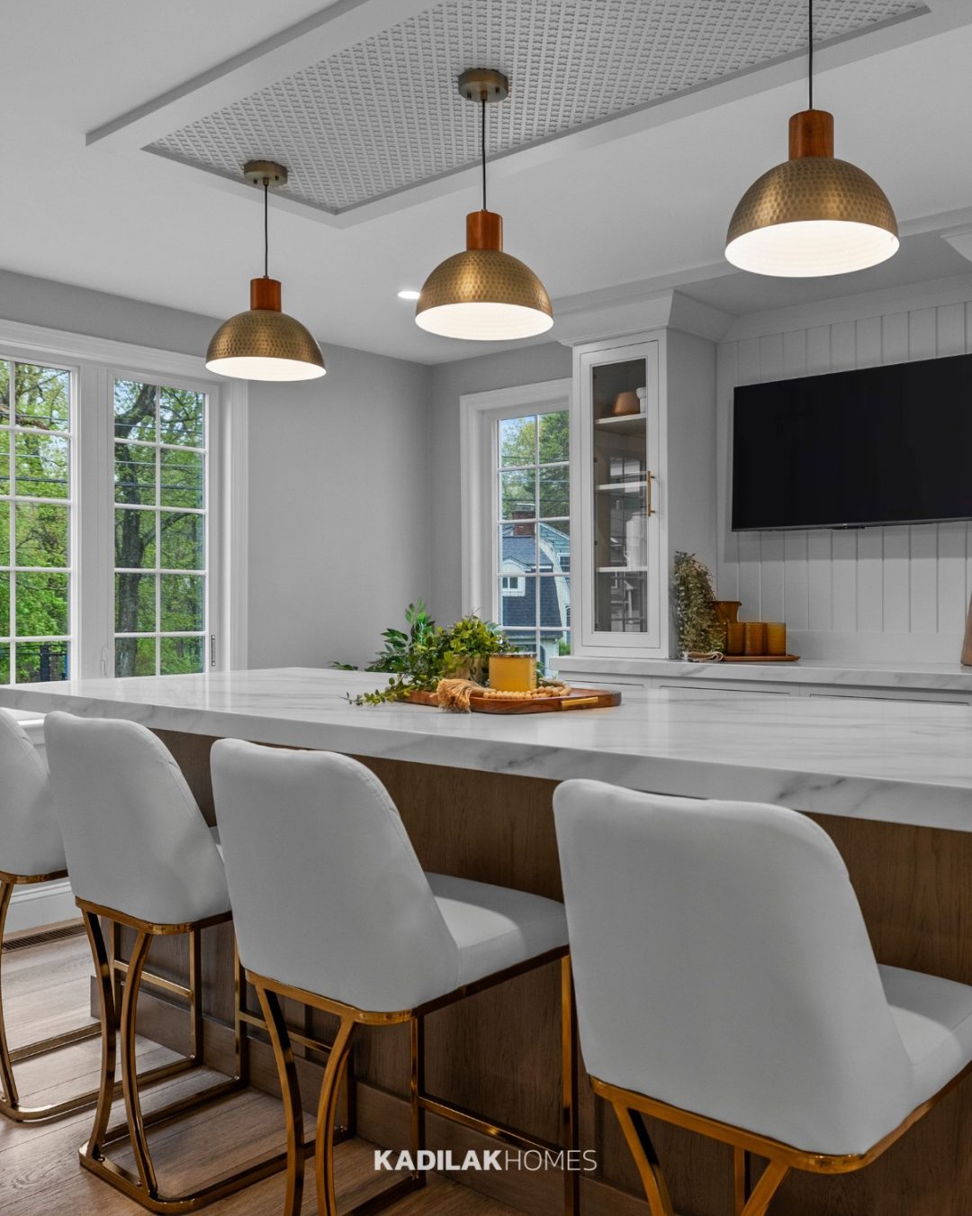Elyona Pendant from Amazon with a hammered brass dome shade hanging above a modern kitchen island with white quartz countertops.