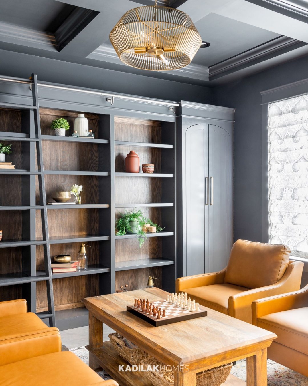 Kaiya Geometric Pendant by Capital Lighting in a warm brass finish mounted in a modern home office with dark built-in bookshelves.