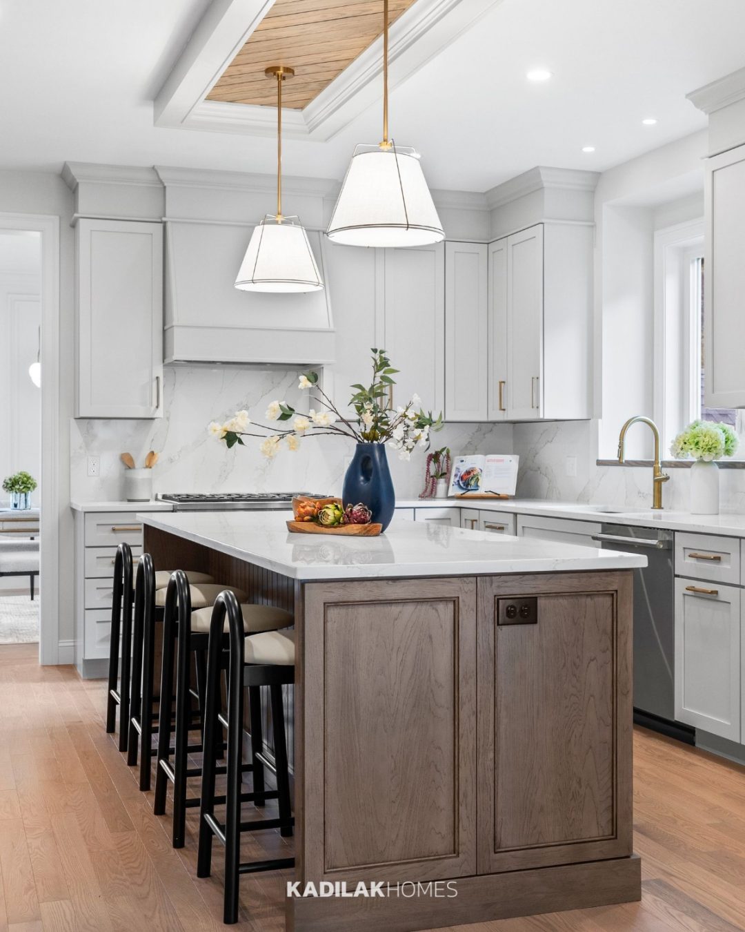 Bertan Fabric Drum Chandelier by Wade Logan with white fabric shades and brass accents hanging above a modern kitchen island.