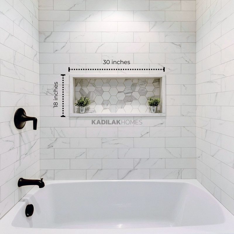 White shower with marble look subway tile, and an oversized horizontal shower niche measuring 30 inches by 18 inches, finished with hexagon accent tile.