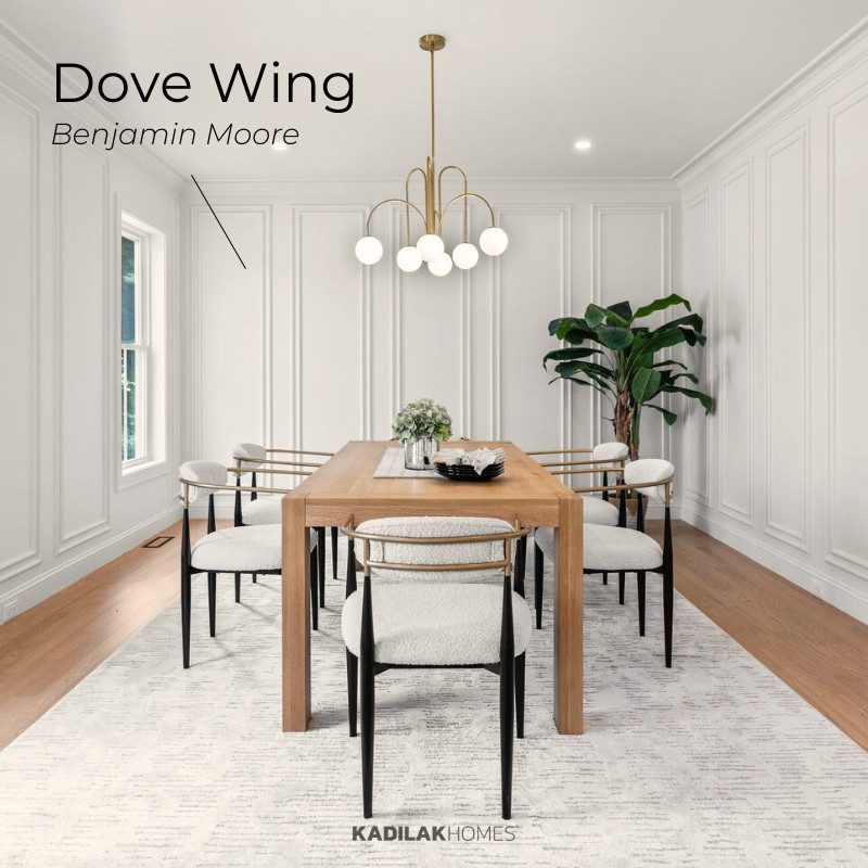 Elegant dining room featuring Benjamin Moore Dove Wing, a soft and warm off-white, as part of a timeless color palette for home. The space showcases classic wall paneling, a modern wood dining table, upholstered chairs, a gold chandelier, and natural accents for a cozy yet sophisticated look.
