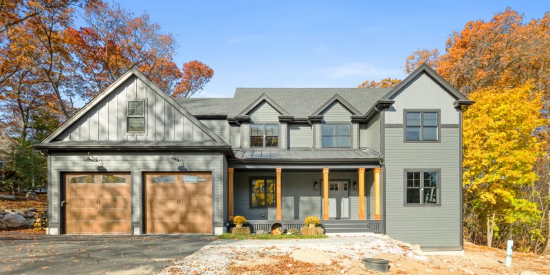 Kadilak home exterior, dark house with black trim and wood garage doors