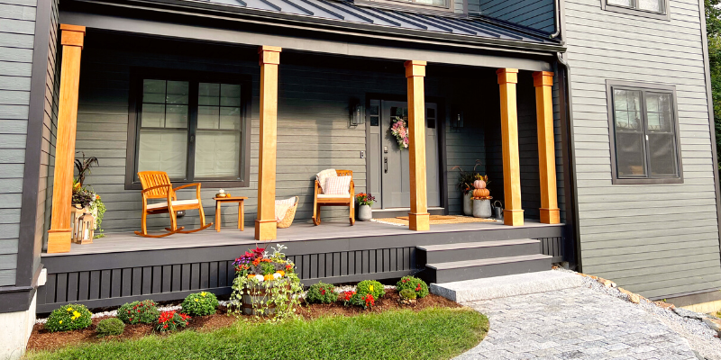 fall front porch ideas, dark house with black trim, porch with wood posts, porch with wood columns, hardie plank siding, house with black windows, front porch idea, cozy outdoor seating, pumpkin decor