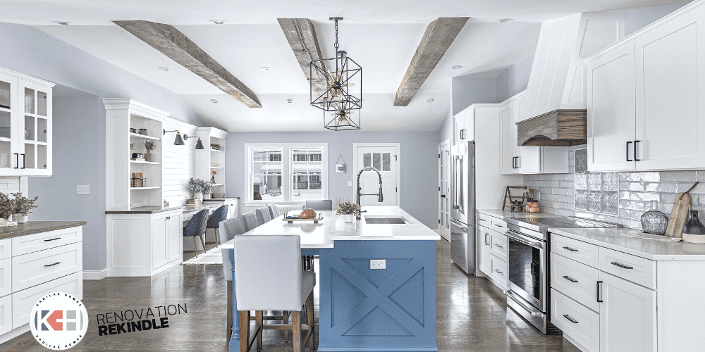 wood ceiling beams, blue kitchen island, cage pendant lights, black and gold lighting, 2 tiered island, double height kitchen island, kohler simplice professional faucet, range hood with wood trim, wood ceiling beam ideas