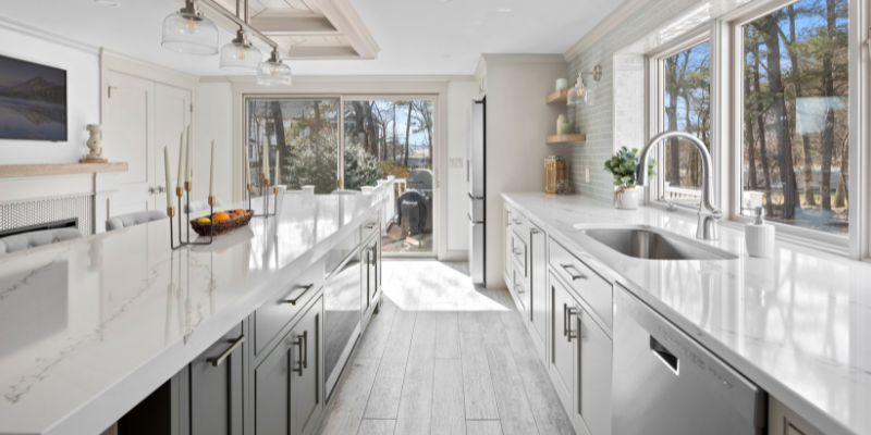 Essential kitchen renovation tips, kitchen budget tips, kitchen with plank tile floor and dark green island, 2" thick quartz counters, earthy neutral kitchen design, surviving a kitchen renovation