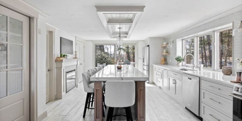 kitchen renovation with island with seating on 2 sides, large window over kitchen sink, fireplace in kitchen, tv in kitchen, off white trim color