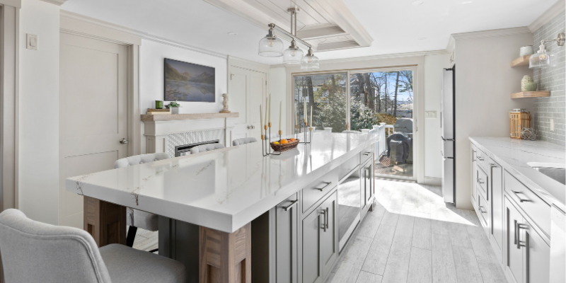 kitchen renovation with island with seating on 2 sides, large window over kitchen sink, fireplace in kitchen, tv in kitchen, off white trim color