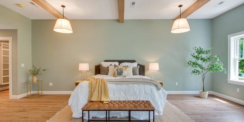 Primary suite with high vaulted ceilings, wood beams, sage green walls, and a mini bar with a fridge, sink, and a sitting area.
