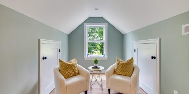 Primary suite with high vaulted ceilings, wood beams, sage green walls, and a mini bar with a fridge, sink, and a sitting area.