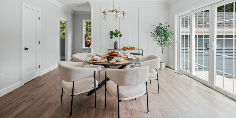 Dining room with 10' sliding door and board and batten accent wall, gold chandelier with clear globes, medium toned stained hardwood floors