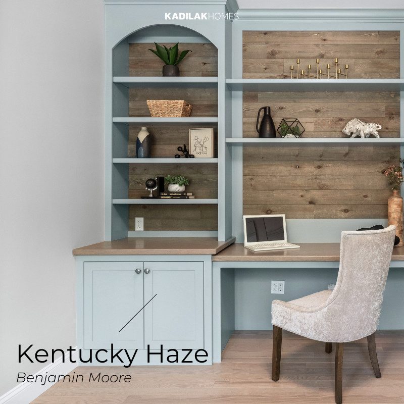 Home office featuring Benjamin Moore Kentucky Haze, a soft, muted blue that adds a calm and inviting touch. The built-in desk and shelving, accented with natural wood tones and styled with modern décor, create a cozy and functional workspace with an earthy neutral color palette for home.