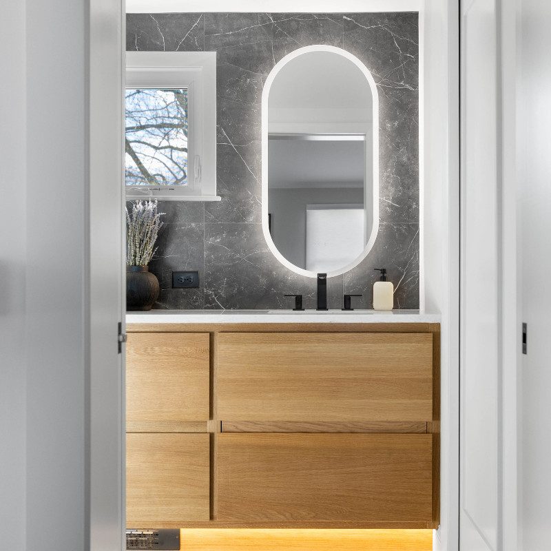 Modern bathroom with LED backlit mirror and soft under-vanity lighting beneath a floating wood vanity.