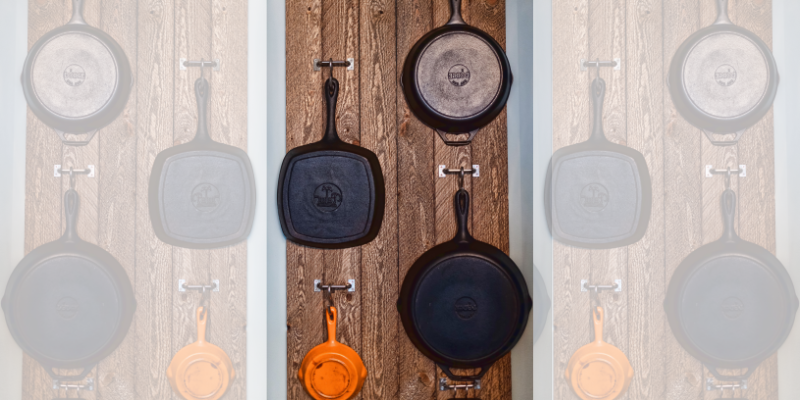 Small kitchen storage and organization idea of hanging pans on the wall with a wood background